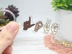 a person holding a keychain with stickers on it that say peace and hand gestures