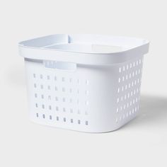 a white plastic basket with holes on the bottom and sides, sitting against a gray background