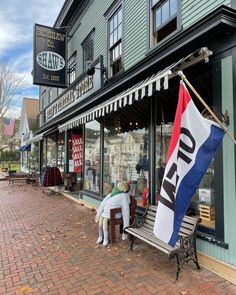 two people sitting on a bench in front of a store with an american flag hanging from the window