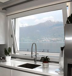 a kitchen with a large window looking out at the water and mountains in the distance