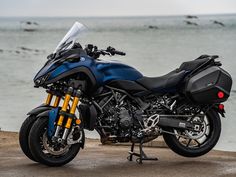 a blue and black motorcycle parked next to the ocean