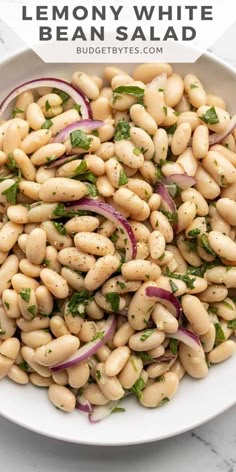 white bean salad with onions and herbs in a bowl on a marble countertop, with the title above it reading lemony white bean salad