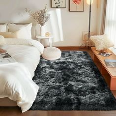 a bedroom with a large bed and black rugs on the floor, along with pictures hanging on the wall