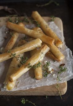 some food is laying on wax paper and garnished with thyerope sprigs