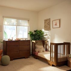 a baby crib in the corner of a room with a potted plant next to it