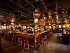 an old fashioned bar with wooden stools and tables in the center, along with many lights on either side