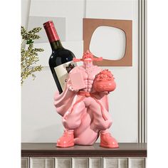 a pink statue holding a bottle of wine on top of a table next to a vase