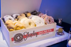 a box filled with assorted donuts sitting on top of a table next to candles