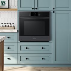 an oven built into the side of a blue cabinet in a kitchen with wooden floors