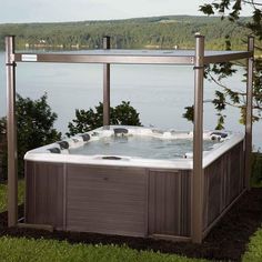 a hot tub sitting on top of a lush green field next to a body of water