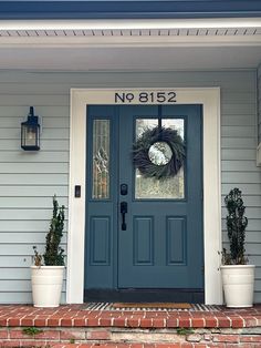 a blue front door with a wreath and two white planters on the side of it