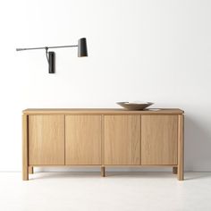 a wooden sideboard with two lights on it and a bowl in front of it