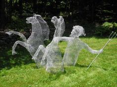 three wire sculptures in the grass with one holding a stick and another standing on its hind legs