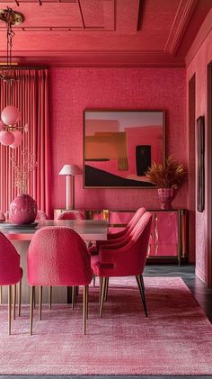 a dining room with pink walls, chairs and rugs on the floor in front of a painting