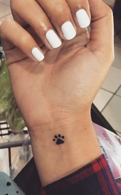 a woman's hand with a small dog paw tattoo on her left wrist,