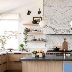 a kitchen with marble counter tops and wooden cabinets, along with hanging lights above the stove