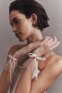 a woman in a white dress with her hands wrapped around her neck and wearing a veil over her shoulder