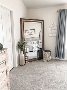 a mirror sitting on top of a wooden dresser next to a bed in a bedroom