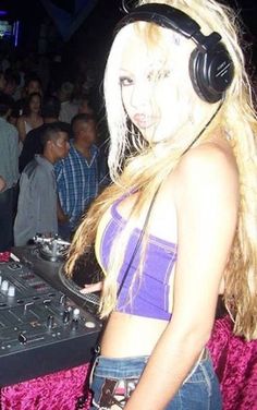 a woman wearing headphones standing in front of a dj mixer