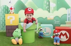 a baby in a red hat is sitting on a green box with stuffed animals and other toys