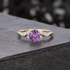 a purple and white diamond ring sitting on top of a box