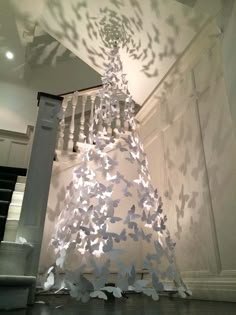 a white tree with lots of butterflies on it's branches in the middle of a room