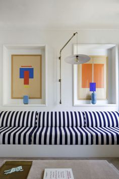 a blue and white striped bench in front of two framed pictures on the wall above it