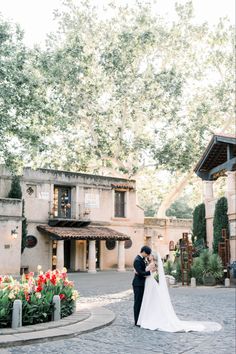 a bride and groom standing in front of a house