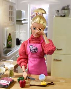 a barbie doll standing in front of a cutting board with food on it and looking at the camera