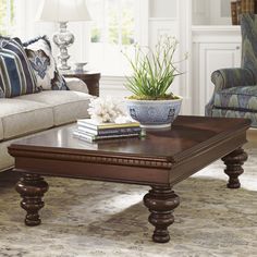 a living room filled with furniture and a plant on top of a wooden coffee table