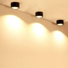 three lights are on the ceiling above a bed in a room with white walls and flooring