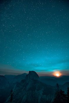 the night sky with stars above mountains and trees