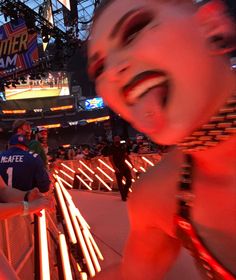 a woman with her mouth open standing in front of a crowd at a sporting event