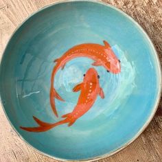 two orange fish swimming in a blue bowl