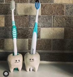 two toothbrushes sitting next to each other in front of a brick wall