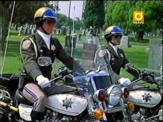 two police officers riding on the back of a motorcycle in front of a gravestone