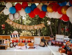 an outdoor picnic with balloons and condiments on the table