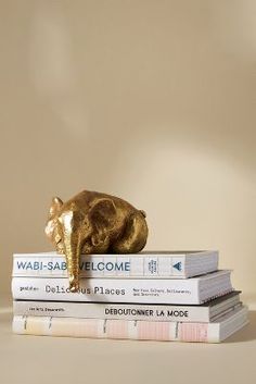 three books stacked on top of each other with a gold elephant figurine atop them