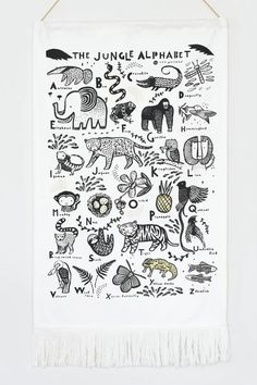 the jungle alphabet tea towel hanging on a white wall with black and white images in it