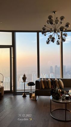 a living room filled with furniture and large windows overlooking the cityscape in the distance