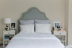 a bed with white linens and pillows in a small room next to two nightstands