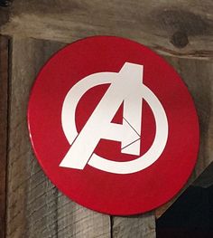 a red and white sign with the avengers symbol on it's side hanging from a wooden wall