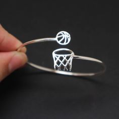 "Basket ball bangle bracelet is handmade with its own uniqueness. It can be bought as a gift for any occasion like birthday gift, wedding gift, travel gift, souvenir and etc. If you need rose gold plating or yellow gold plating, please contact us, we will advice you on the additional fees applicable. Base Material: Sterling Silver Size: 10mm (Approximately) Bangle wrist size: Adjustable / Please give us your wrist circumference. Thickness: 1.5mm / 0.059 Inch Metal Stamped: 925 Crafting Time: 7 - Adjustable Hoop Bracelets As Gift, Sports Gift Basket, Bola Jaring, Netted Bracelet, Muzică Rock, Basketball Jewelry, Personalized Sports Gifts, Basketball Rim, Bola Basket