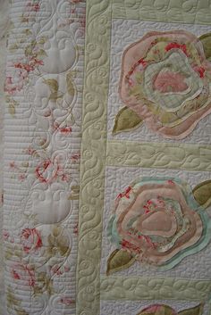 a close up of a quilted wall hanging with flowers on it's side