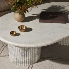 a white marble table with two gold cups on it and a vase filled with flowers