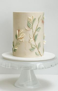 there is a white cake with flowers on the frosting and icing, sitting on a plate