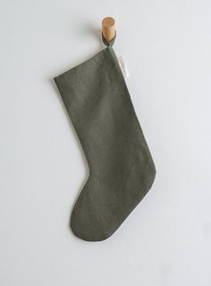 a green christmas stocking hanging on a white wall with a wooden stick sticking out of it