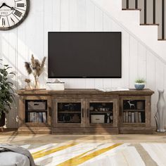 a living room with a large tv mounted on the wall next to a stair case