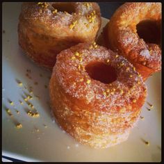 three donuts sitting on top of a white plate covered in sugar and sprinkles