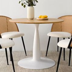 three chairs around a round table with a vase on it and lemons in the middle